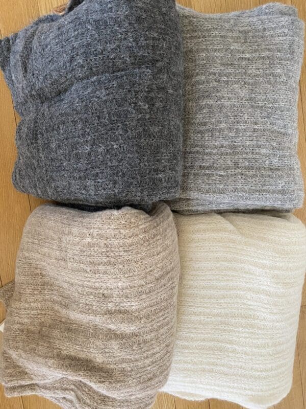 A pile of blankets and pillows in different colors.