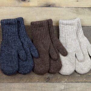 Three pairs of mittens are lined up on a wooden surface.